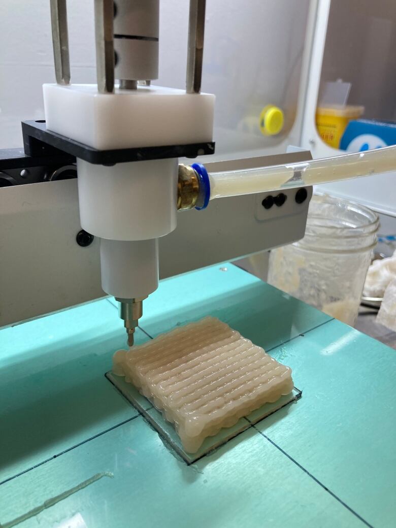 A 3D printer produces a latticed-grid of white liquid gel.