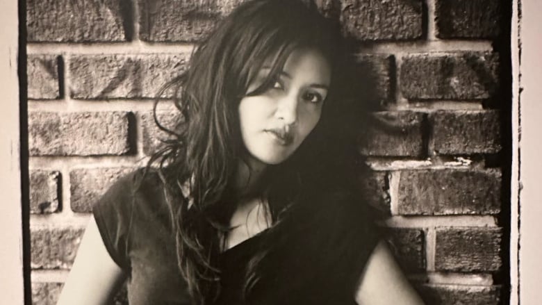 Photo of Paula Toledo in the mid-2000s. It is a black-and-white picture of a woman leaning against a brick wall.