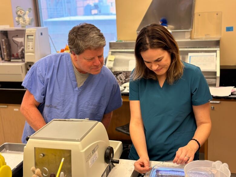 A man and a woman examine a specimen in a laboratory.