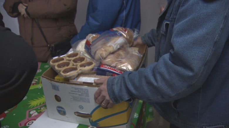 A box of food is carried by somebody wearing a jean jacket