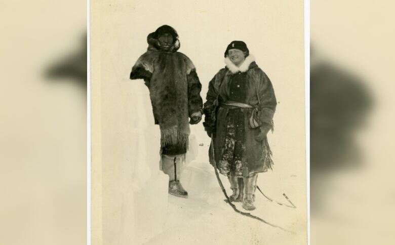 Black and white photo of a man, at left, and a woman standing in snow and wearing seal skin coats