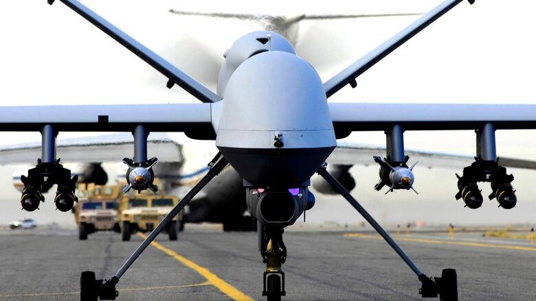 An armed drone taxis down a runway.