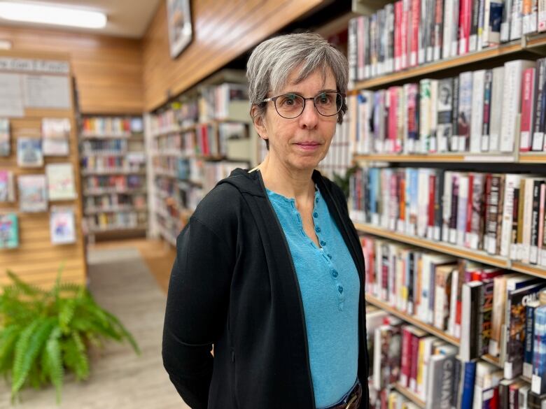 A woman stands inside a library.