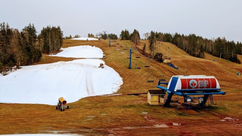 Three large patches of snow are surrounded by brownish-green grass on the slope at Mark Arendz Provincial Ski Park.