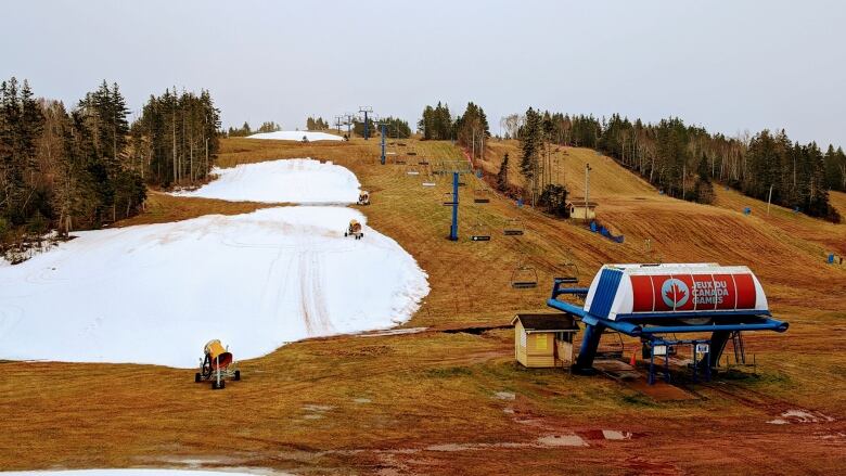 Three large patches of snow are surrounded by brownish-green grass on the slope at Mark Arendz Provincial Ski Park.