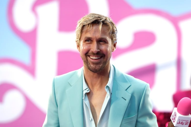 Ryan Gosling smiles while wearing a blue suit at the European premiere of Barbie.