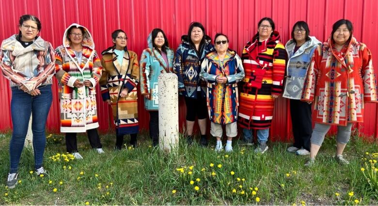 A group of women pose wearing their bespoke coats.