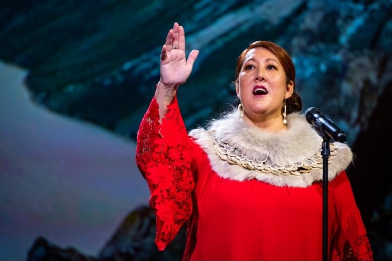 A woman in a red dress signs into a mic