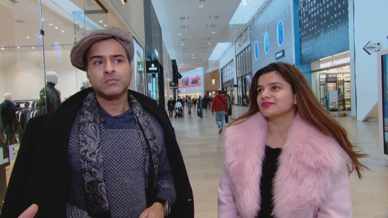 A well-dressed man and woman in a shopping mall. 