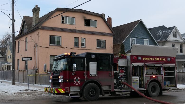 A fire truck is parked outside of a three-storey building with black above a window.