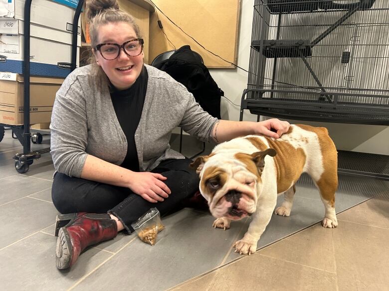 Woman sits on floor petting an English Bulldog.