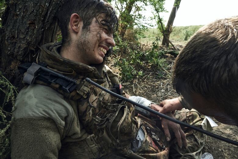 A wounded soldier grimaces as a medic examines him.