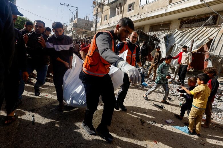 People carry a white sheet that contains a body.