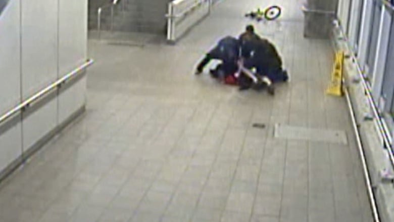 A still taken from CCTV footage shows a struggle between a group of people on the floor of a SkyTrain station.