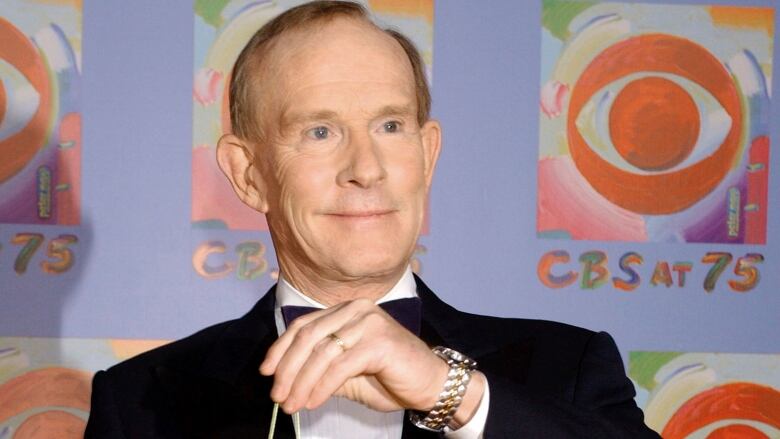 Tom Smothers, in his mid-60s, is shown from the shoulders up wearing a tuxedo and holding the string of a yo-yo 