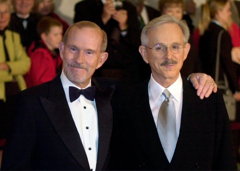 Tom Smothers, left, with his arm around the shoulder of Dick Smothers, both in their 60s in formal attire