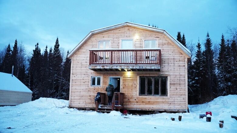 Kids walk into a two-storey wooden cabin. 