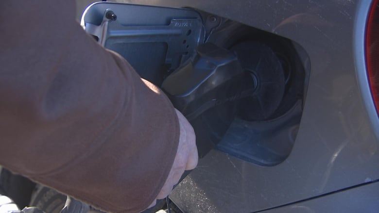 A person's hand is seen on a gas pump.