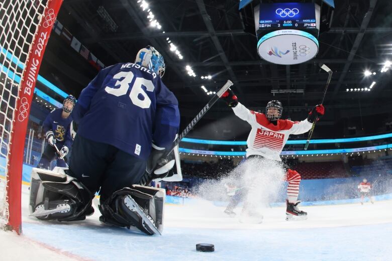 A hockey player raises her arms after scoring a goal.