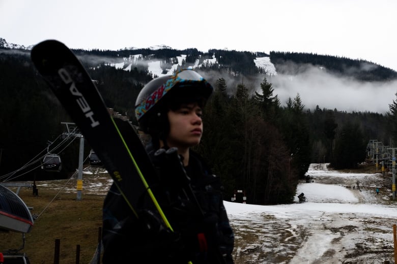 A skier in front of a brown mountain.