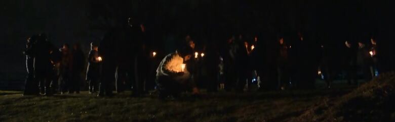 People holding candles in the dark.