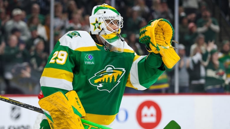 A men's goaltender waves to the crowd.