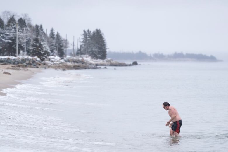 A swimmer walks out of the water after doing a polar bear swim in the Atlantic Ocean.