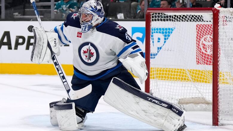 A hockey goalie in blue and white makes a save