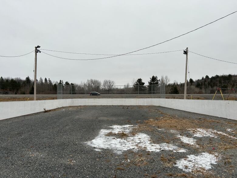 An outdoor skating rink with a visible gravel base, and no ice.