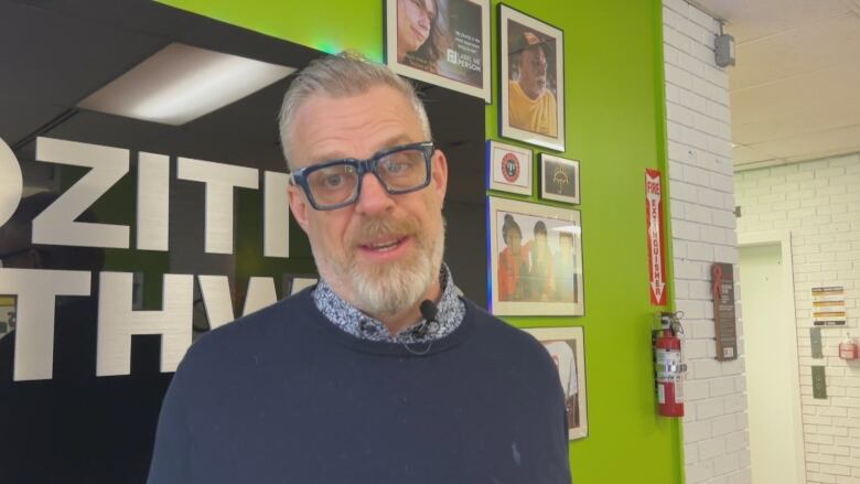 A man with glasses smiles at the camera