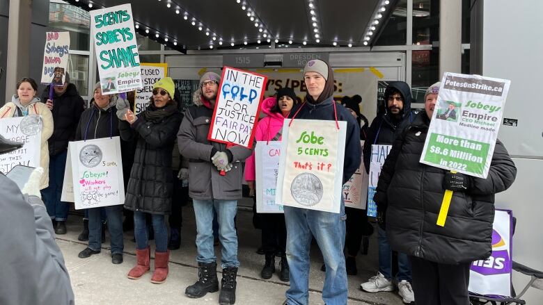 People hold signs demanding fair wages.