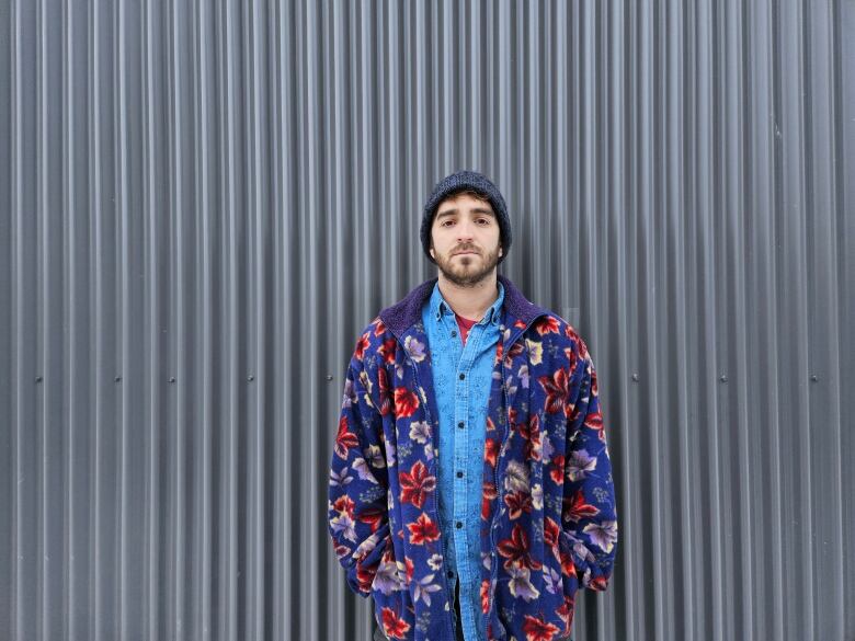 image of matthew toothill, colourful outfit, in front of grey tin siding