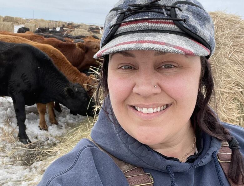 A woman smiles in front her cattle.