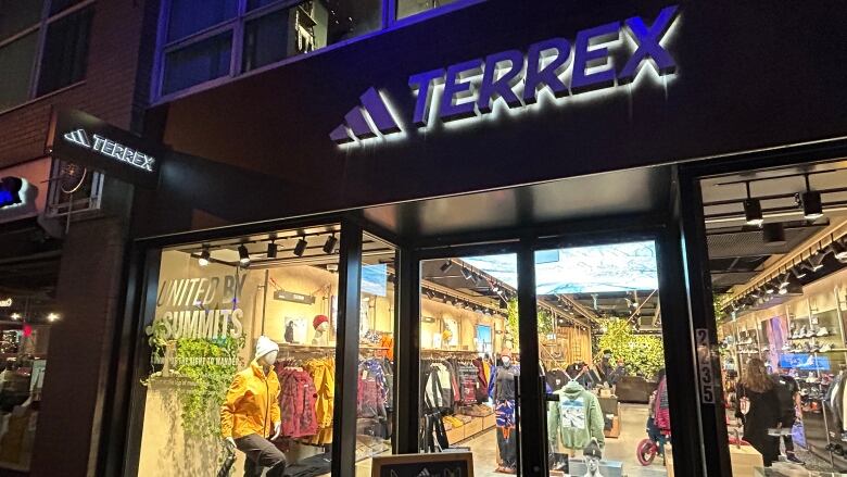 A storefront showing running and outdoor gear is shown at night under a sign reading 'Terrex.'