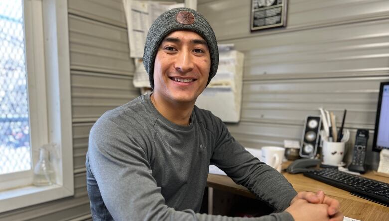 A man with a toque sits inside an office.