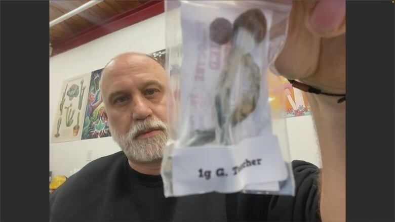 A bald man showing a package of mushroom to the camera