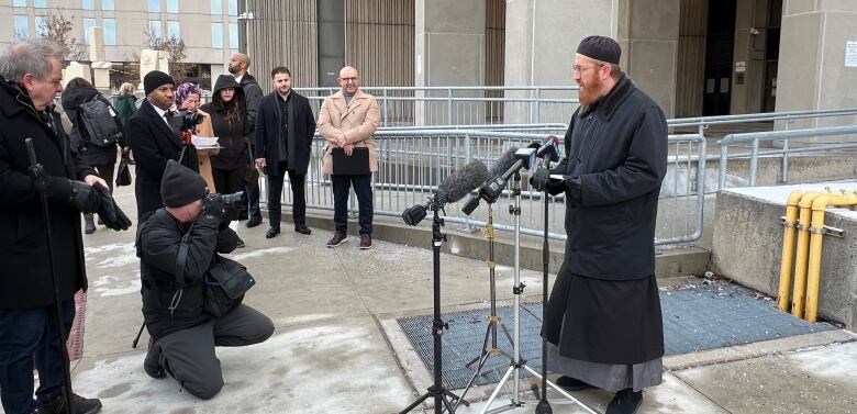 an imam speaks outside a courthouse in front of cameras