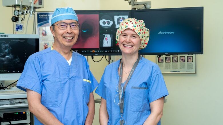 Two people wearing scrubs smile