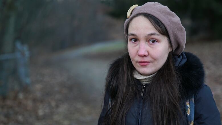 A woman poses for a photo in a park in winter.