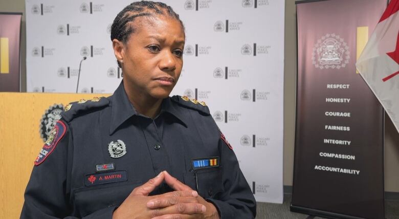 A woman in a police uniform stands in front of a podium.