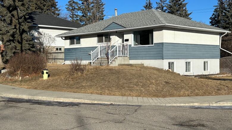 a blue and white bungalow on a corner lot is pictured 