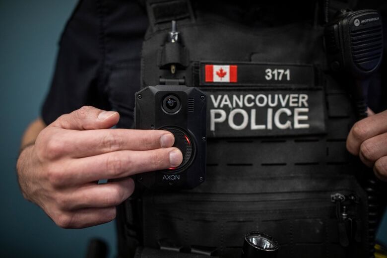 A Vancouver police officer presses a button on a camera attached to his tactical vest.