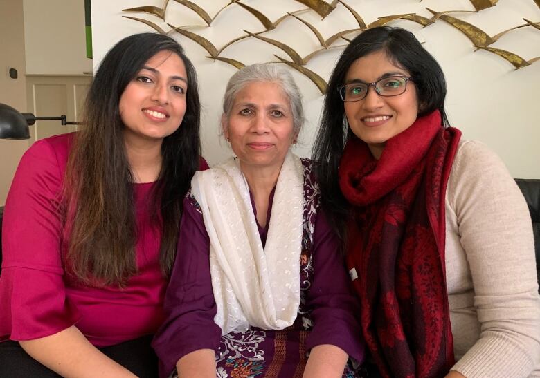 An elderly woman sits in the middle, flanked by her two daughters.