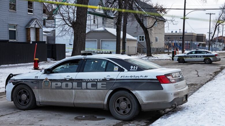 Black and white police cars block a street in the winter