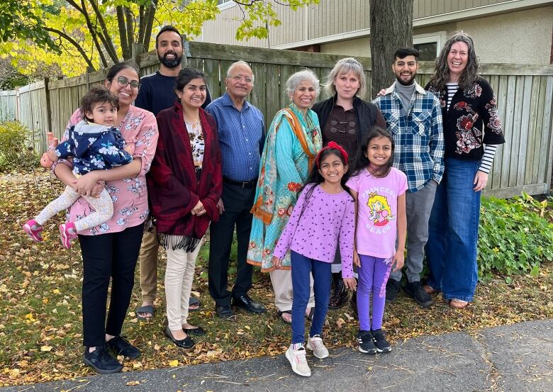 A group of 11 people of various ages and cultures, smiling at the camera.