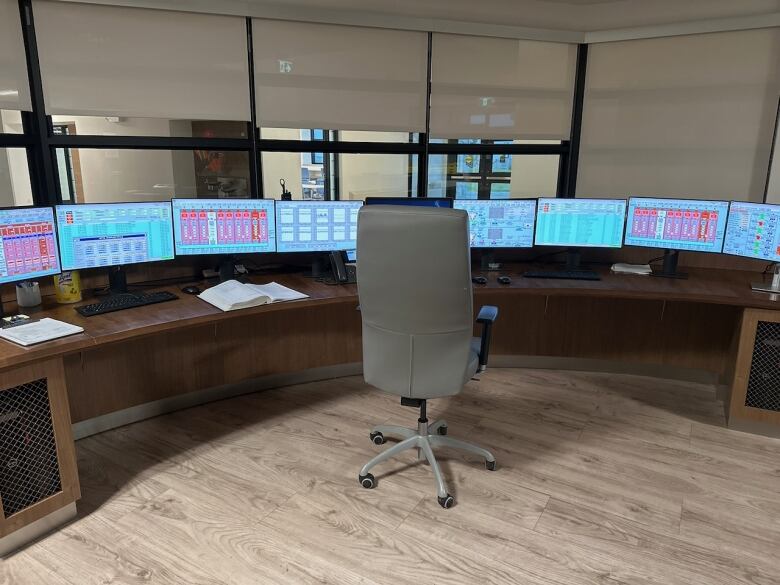 An office desk with a chair and nine monitors. 