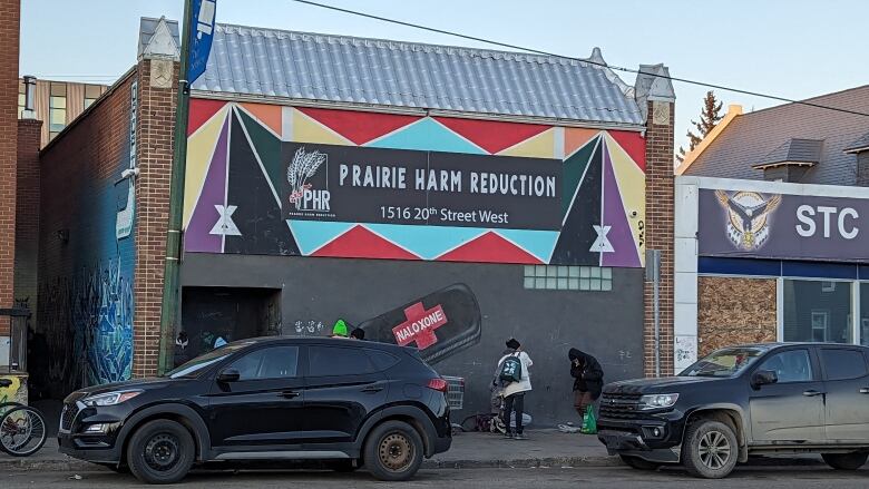 People sit and stand outside of Prairie Harm Reduction -- a facility in Saskatoon.