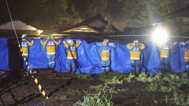 Police officer help in the rescue of a woman in her 90s, who was found alive in a collapsed home in Suzu, Japan.