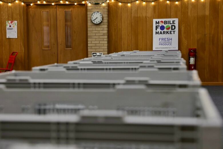 A row of grey crates are lined up on tables. A sign in the back reads 'Mobile Food Market.' 