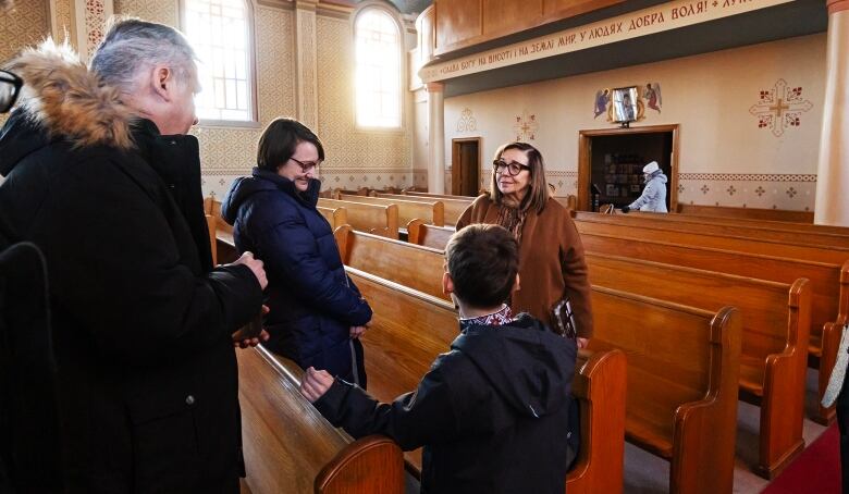 People share a conversation amidst church pews.